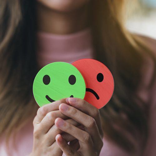 Woman Hands holding sad face hiding or behind happy smiley face, bipolar and depression, mental health concept, personality, mood change, therapy healing split concept.